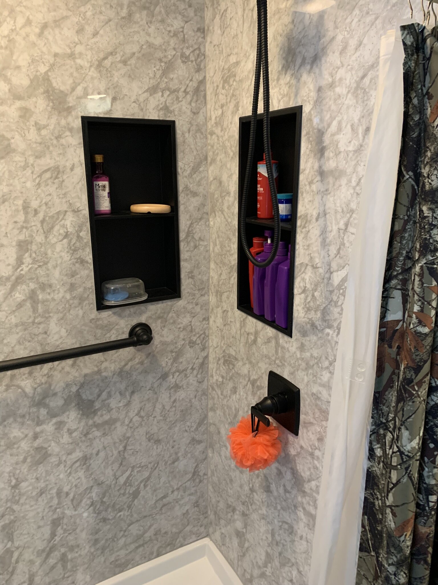 New shower with black grab bars and shelving